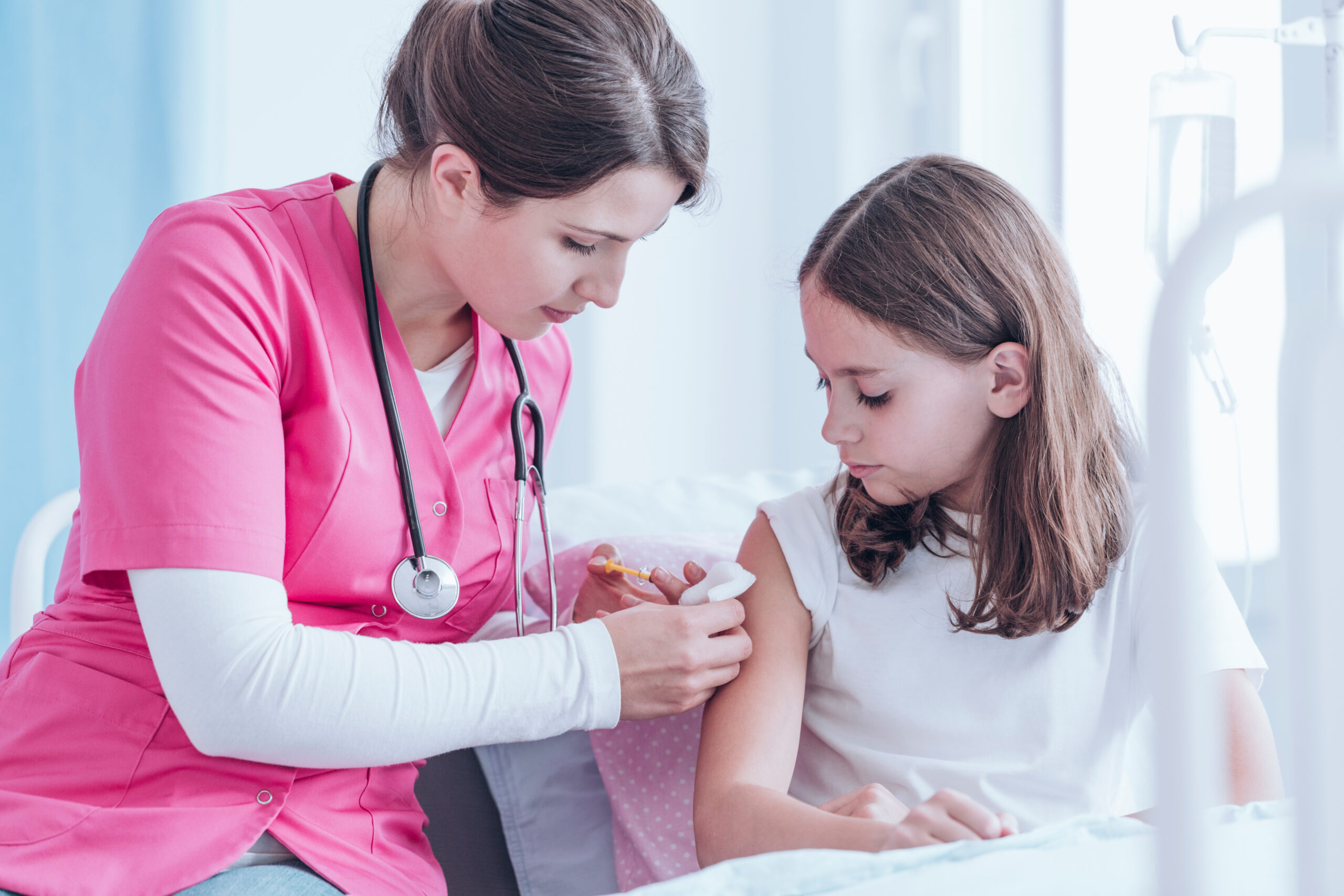 Nurse in pink uniform giving an injection against tuberculosis to a girl